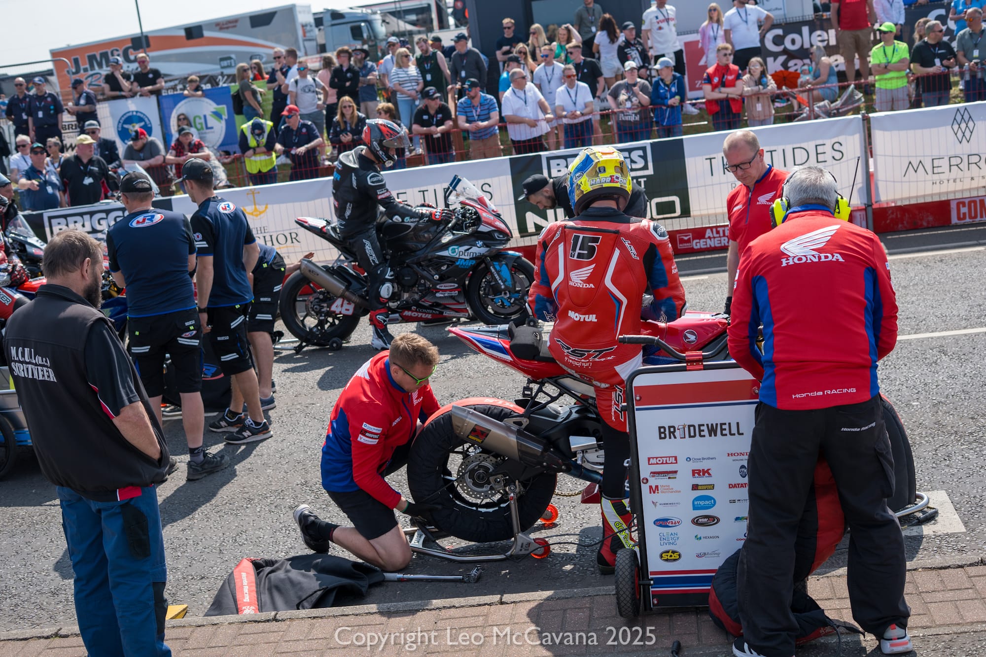 Riders wait patiently for the race to start while crew carry out last minutes preparations.